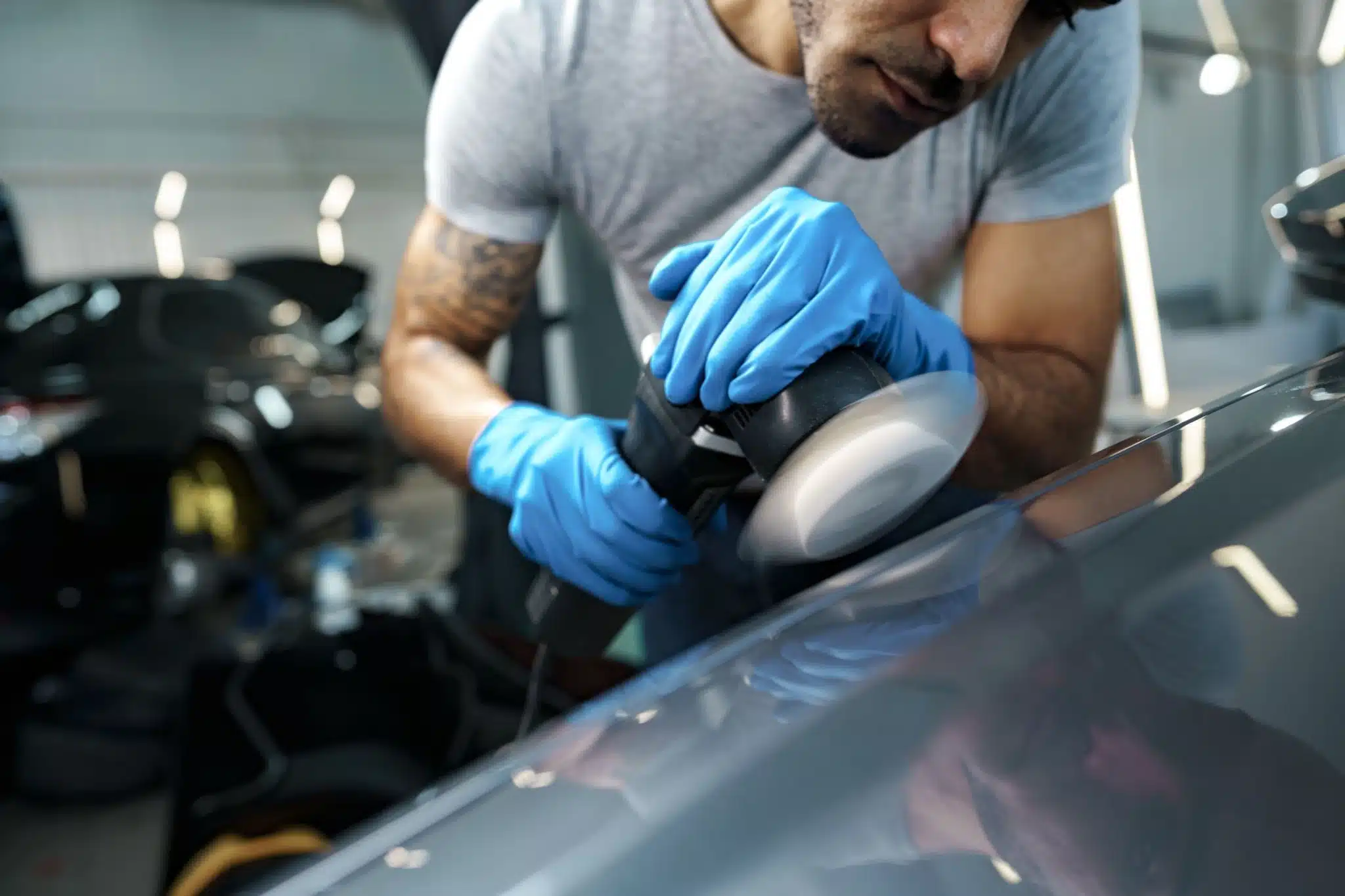 Close-up of a professional detailer carefully working on a car surface with specialized tools, showing attention to detail and expertise