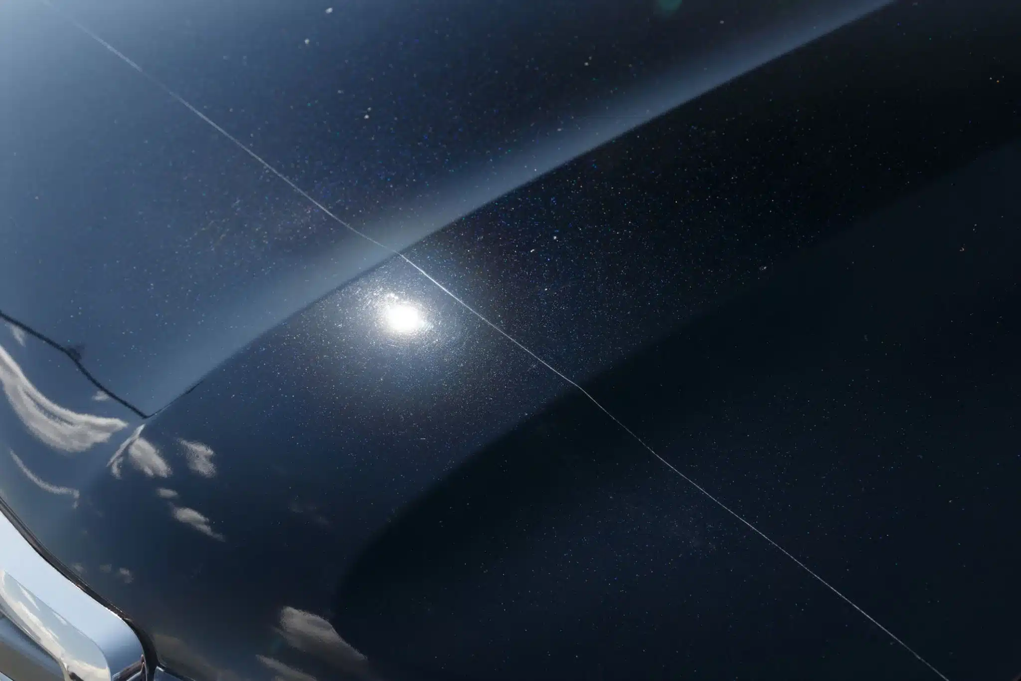 Car Swirl Mark Removal Sydney | Professional Paint Perfection 166 Close-up of black car paint showing visible swirl marks under direct sunlight, circular spider-web pattern clearly visible