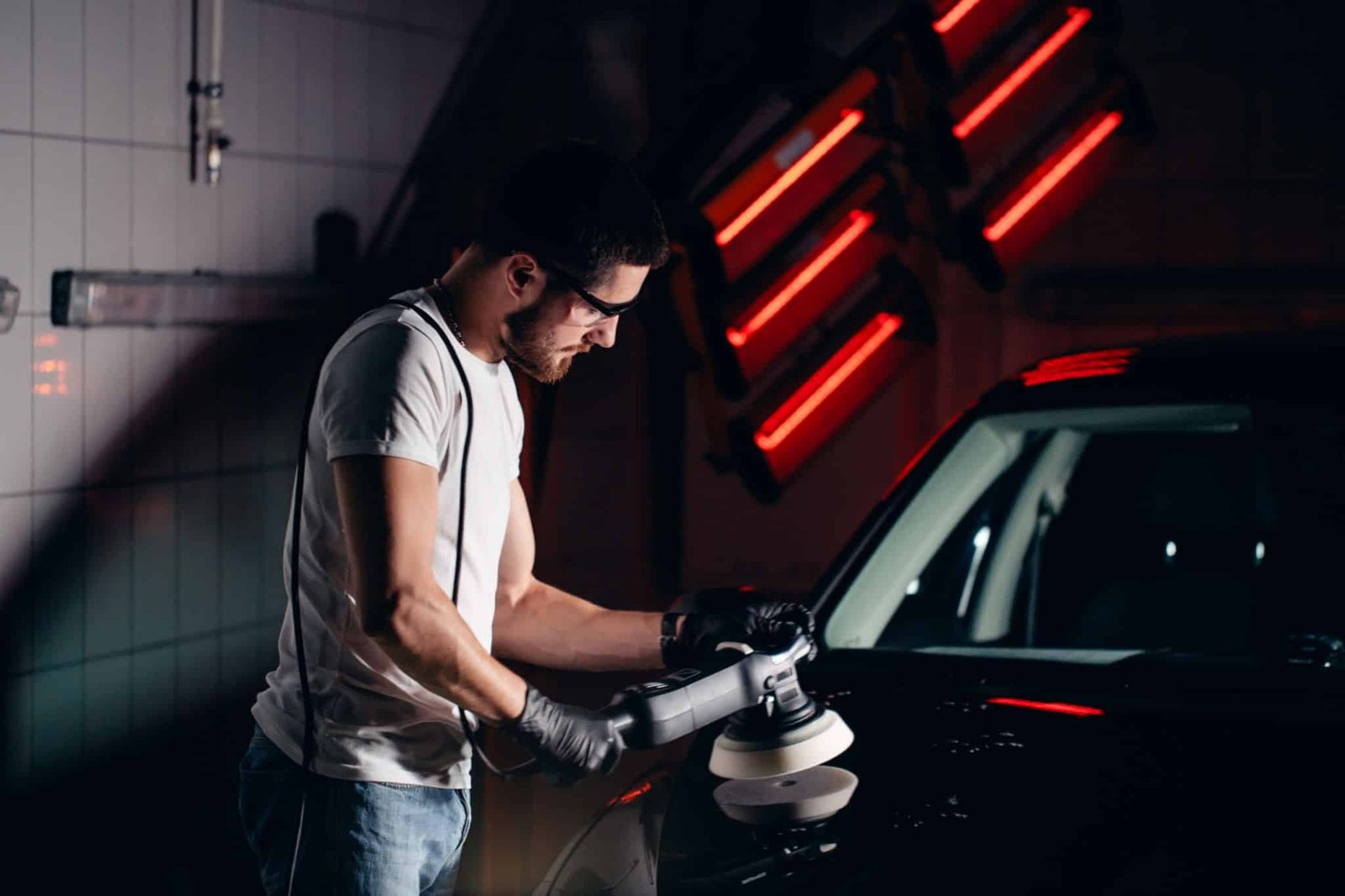 Close-up of a professional technician using a dual-action machine polisher on a dark coloured car panel